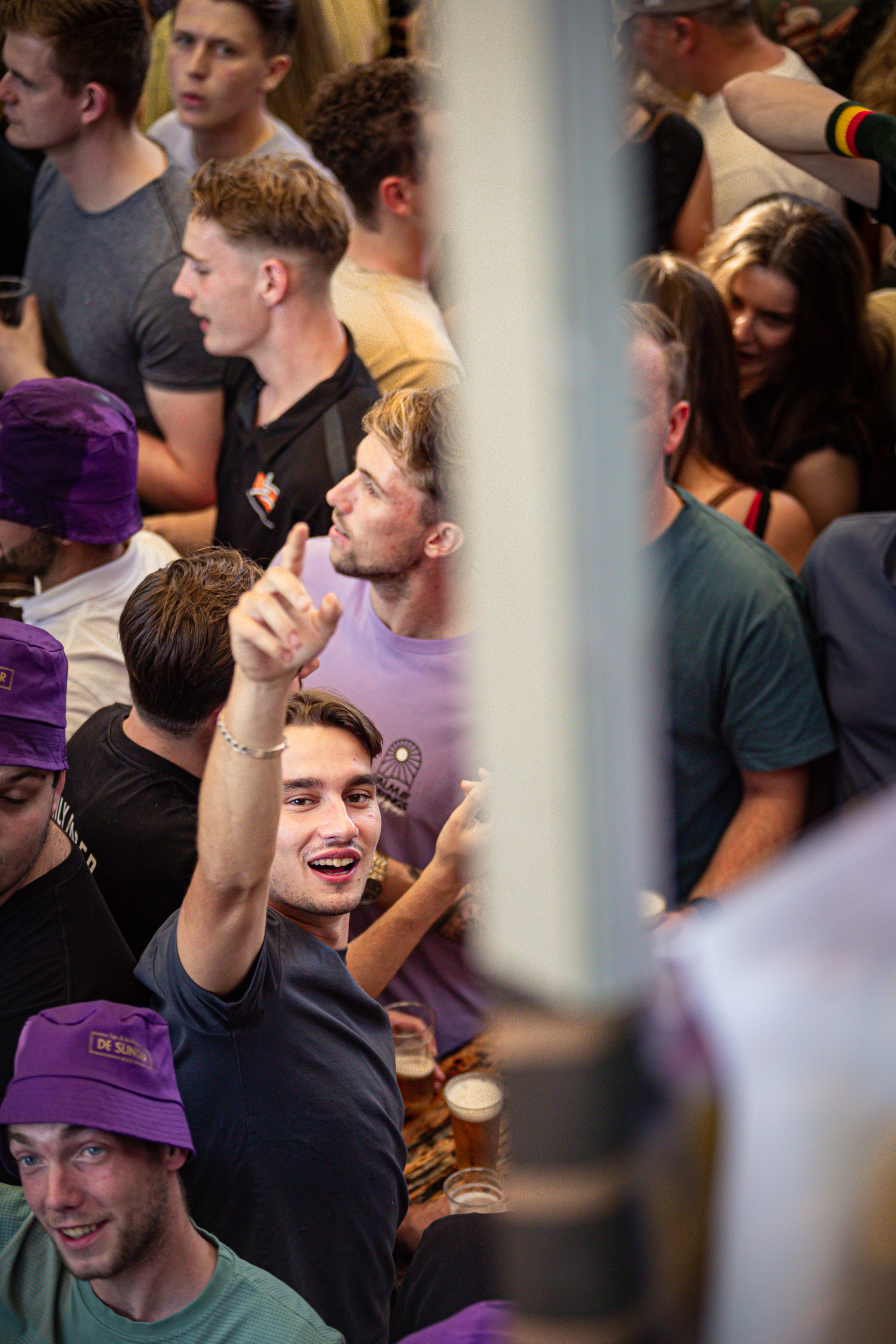 a group of people that are in a bar like setting with one guy holding up his hand and pointing.