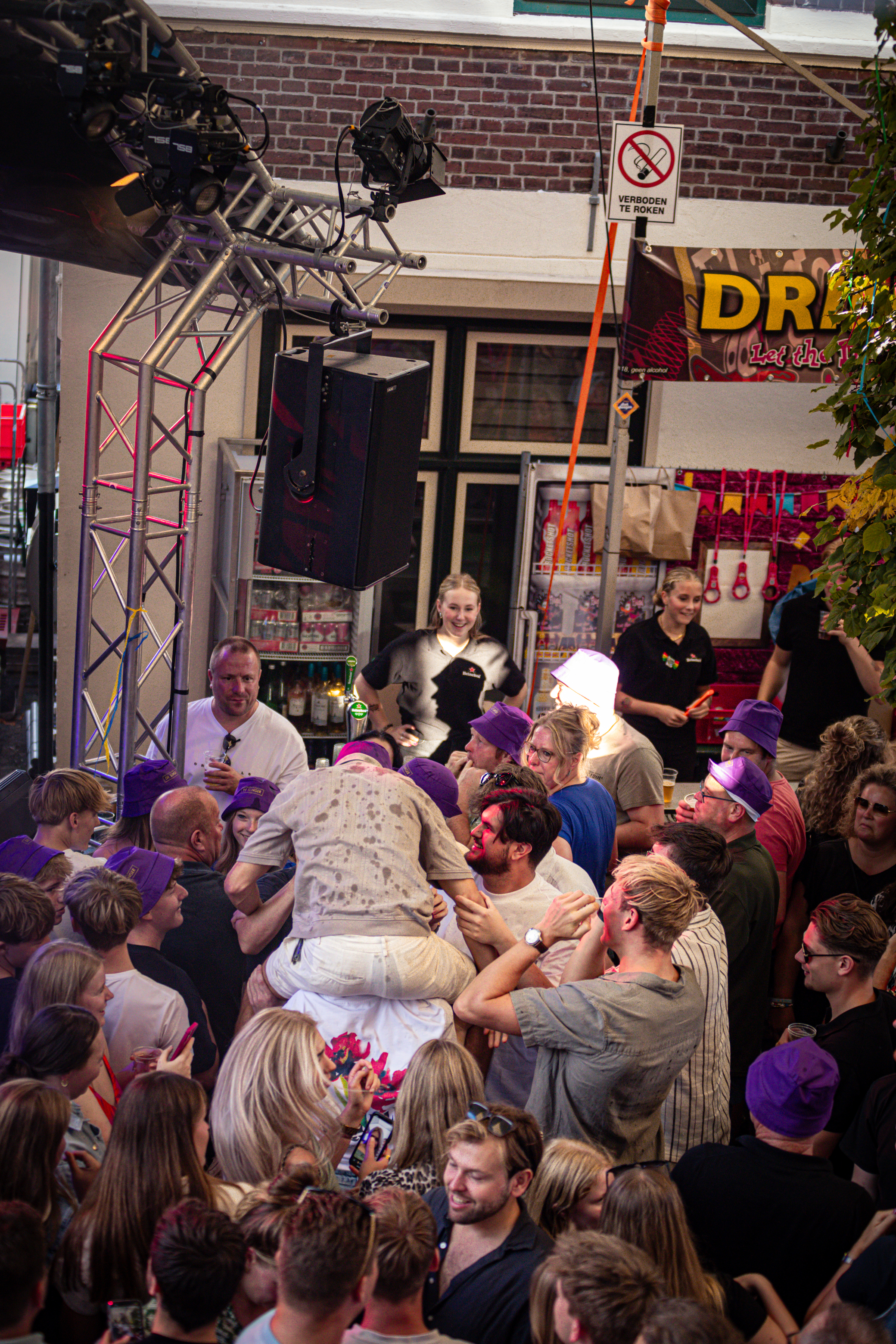 A lively scene from a nightclub where people are enjoying themselves, including one man being carried by the crowd.