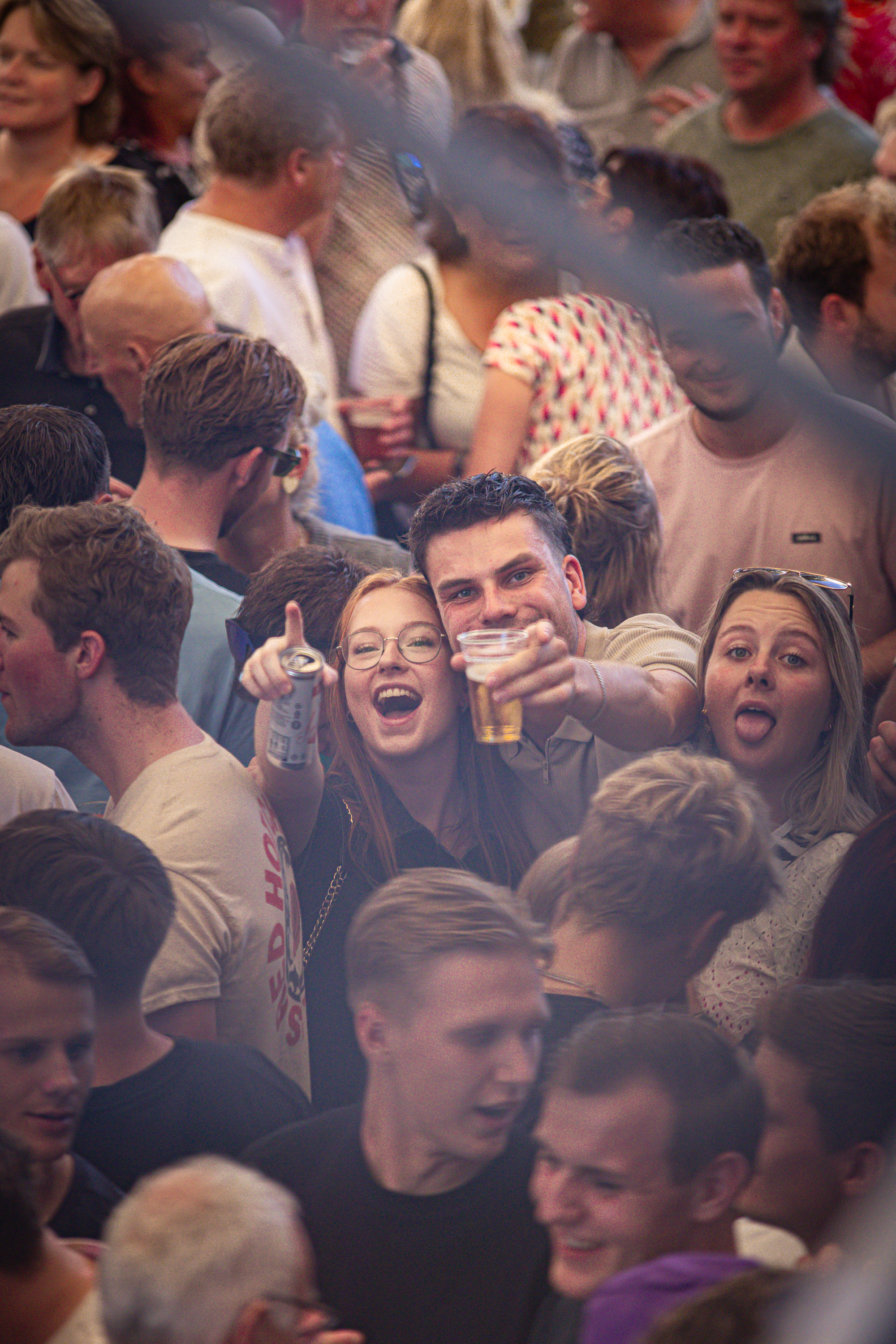 A young man holding a drink and smiling with a group of people at an event.