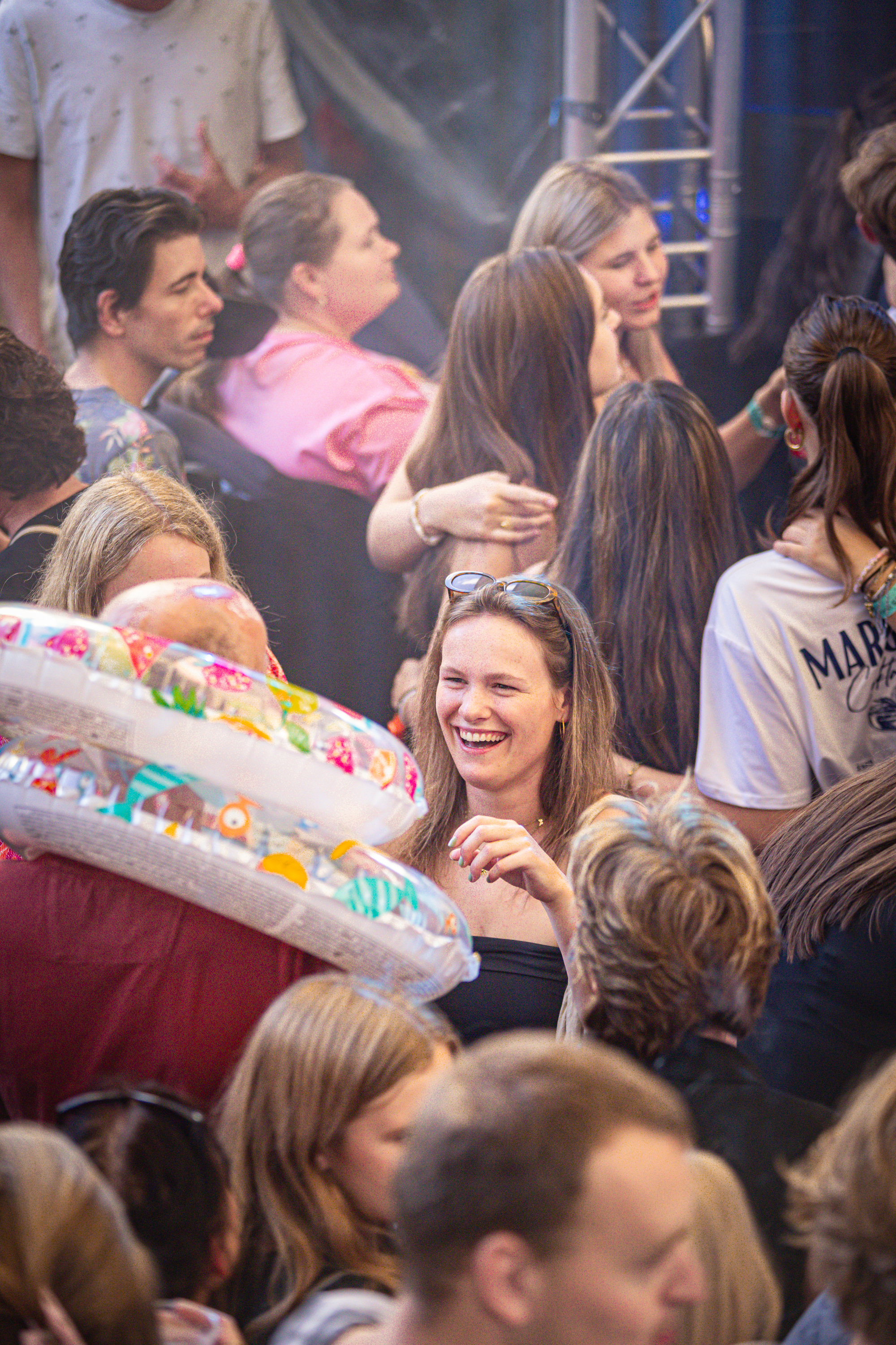 A group of people are at an event, smiling and holding up a colorful float.