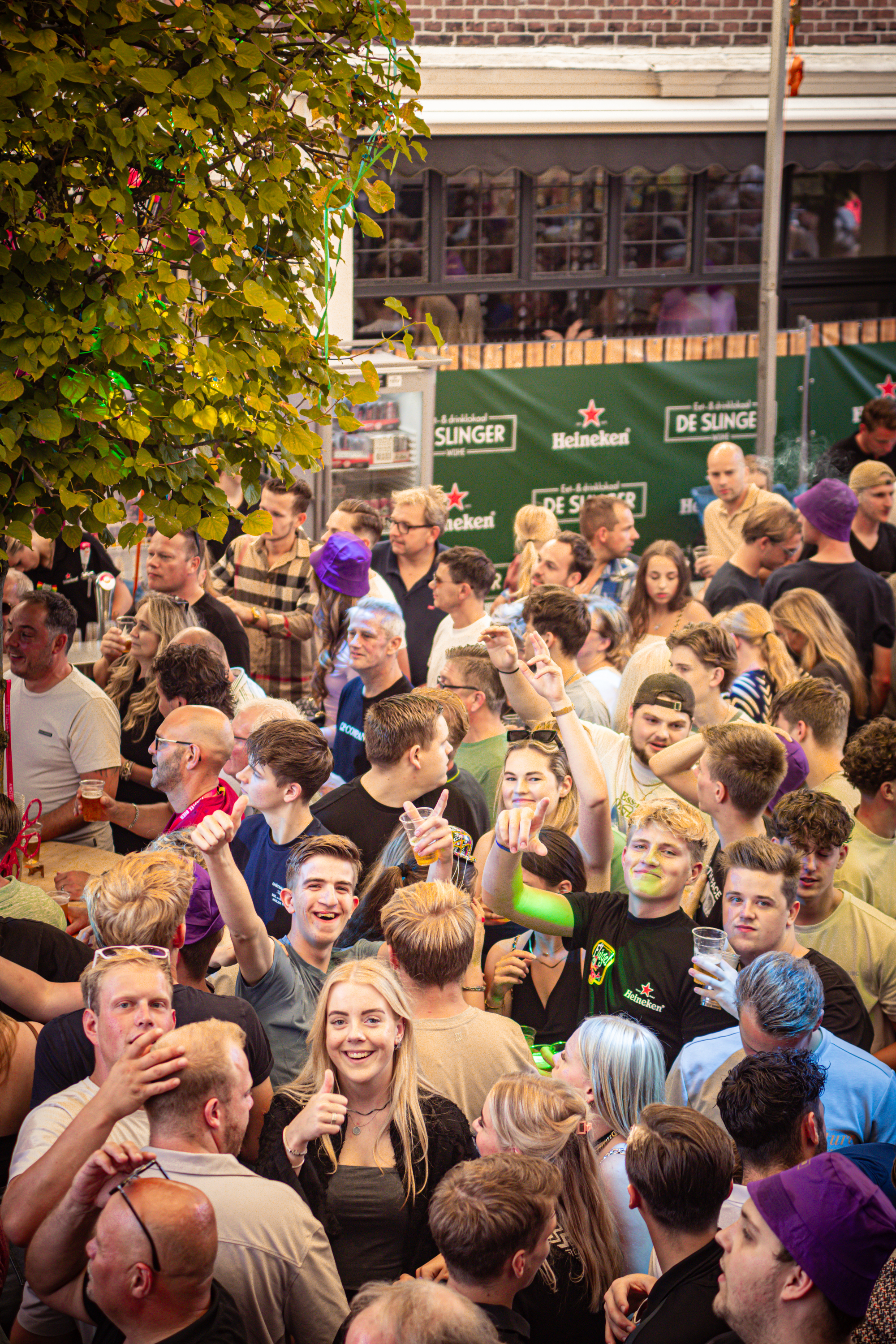 A large group of people gathered together outside of a bar called Slinger.