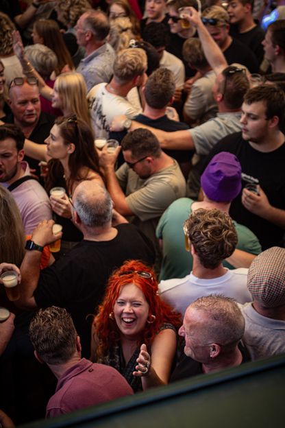 A group of people are laughing and drinking at a bar.