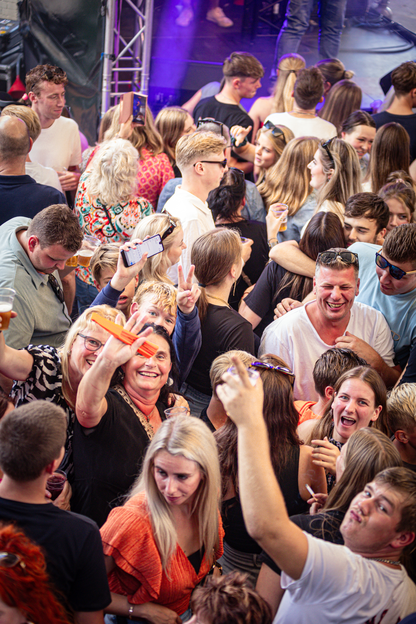 A group of people are celebrating at a party, some holding drinks and others wearing sunglasses.