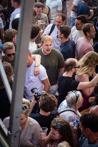 People are gathered for an event and one man is holding a trophy, while another is taking pictures.