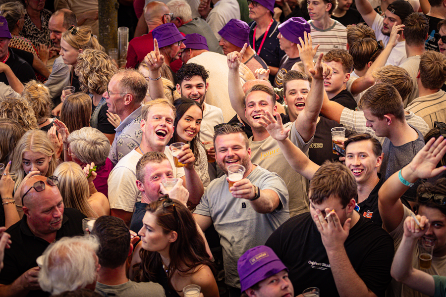 A group of people at a party with one man wearing a purple hat.