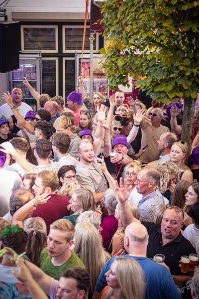 A crowd of people at an event with a purple hat that says "Jugend".