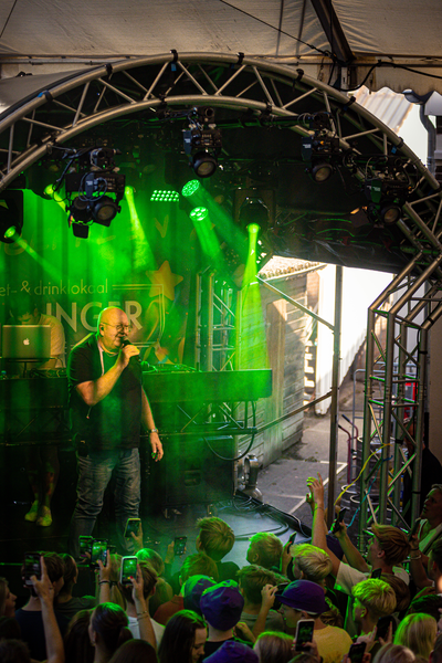 A man on a stage with an audience of people taking pictures at the concert.