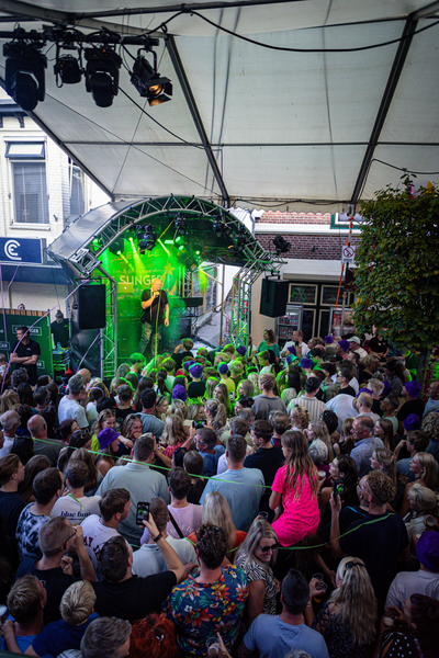 A man is singing on a stage with a crowd watching him.