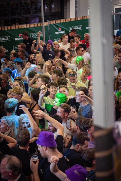 A crowded public event with many people wearing green hats.