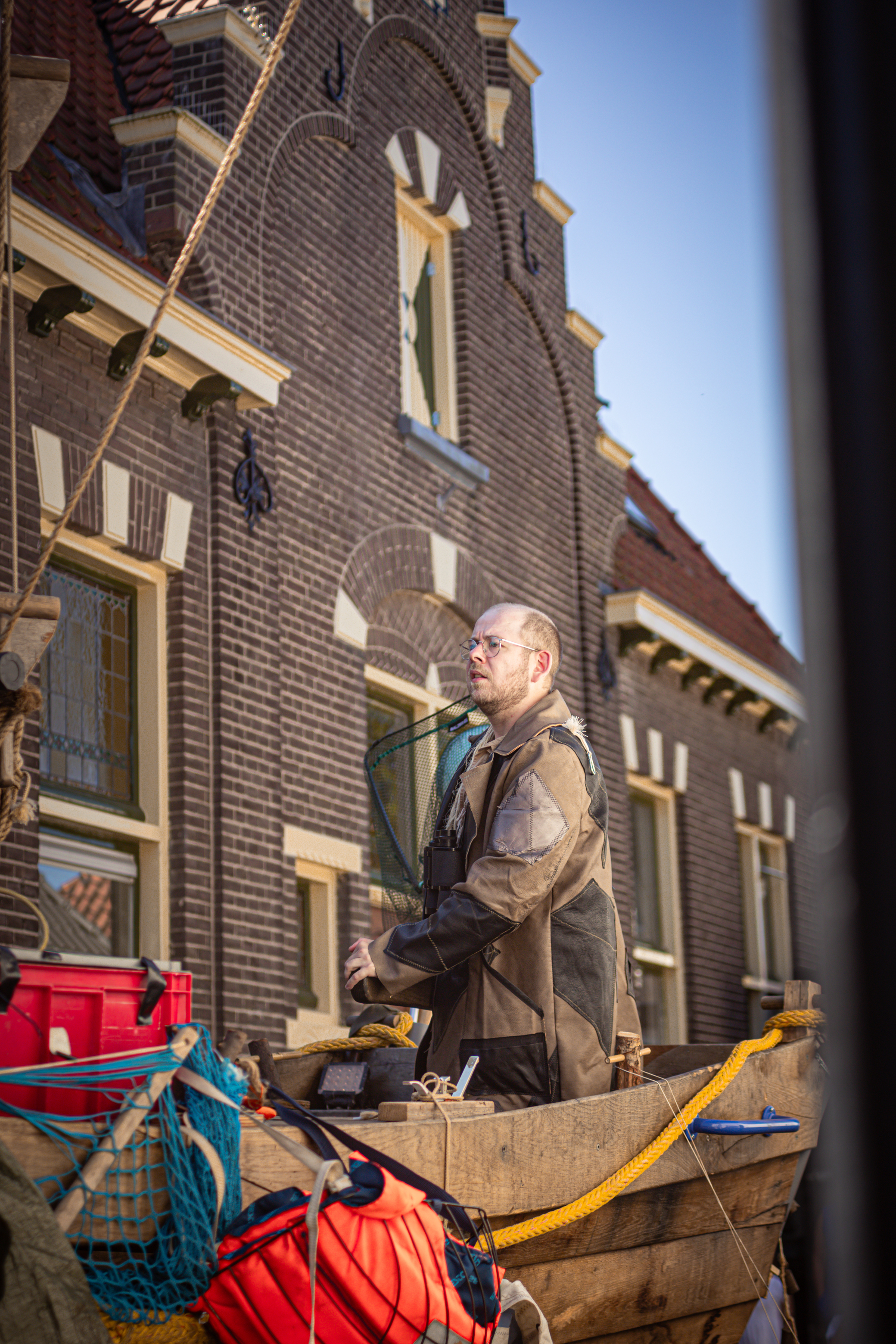 A man is sitting on a wooden bench with fishing rods in his hand.
