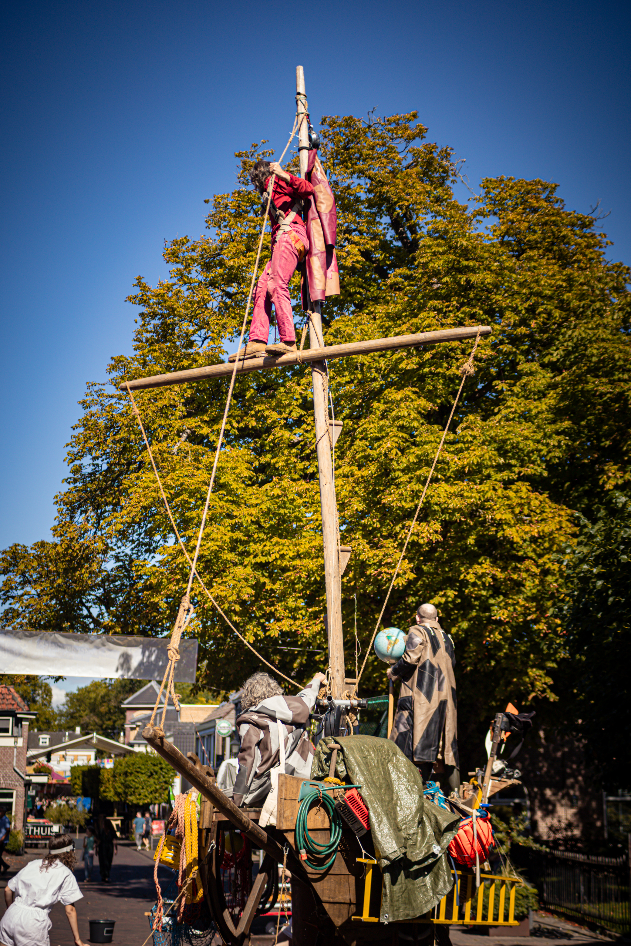 V.IJ.F. Festival: A red and yellow rope bridge made of wooden poles, with people hanging above it.