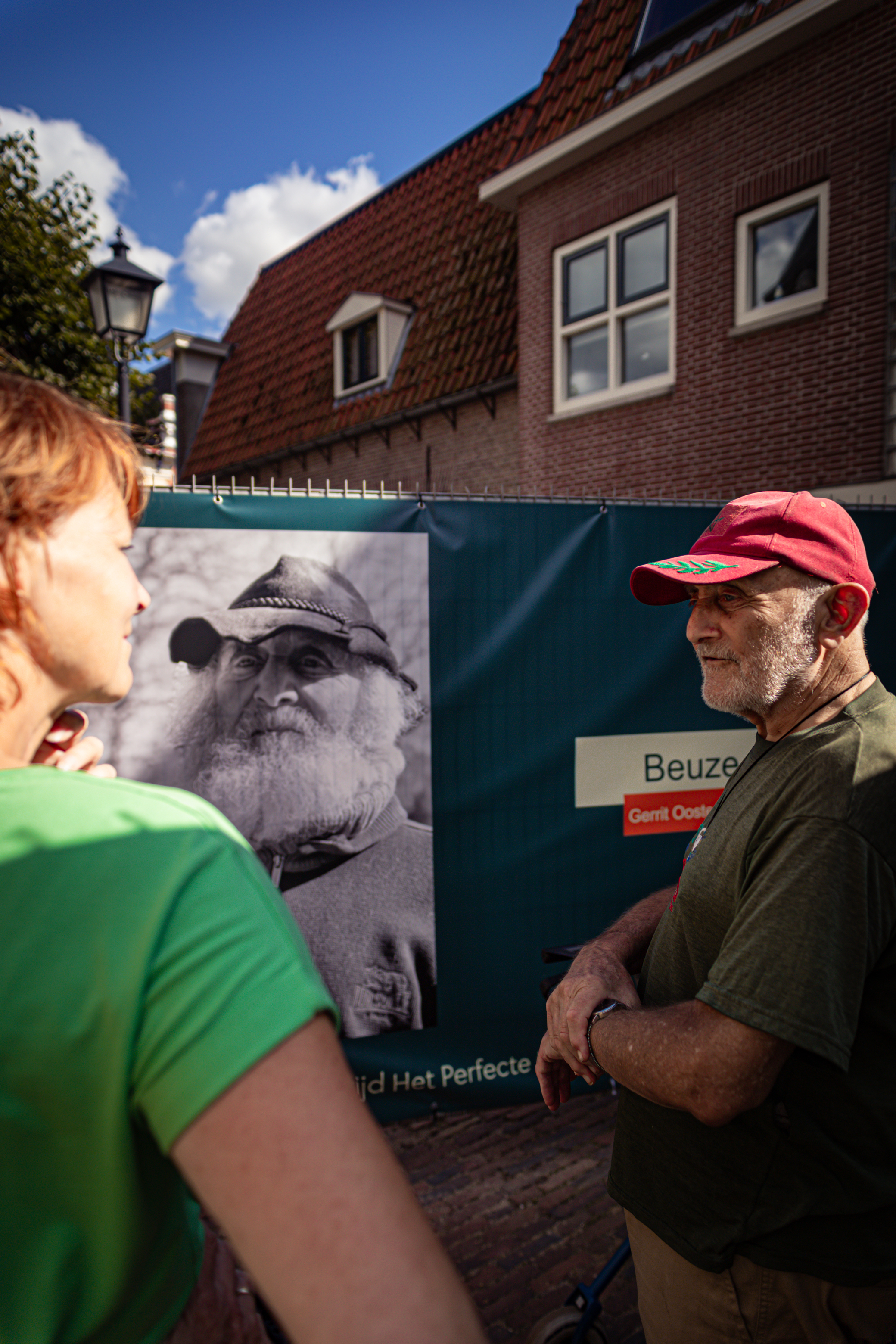 A man in a green shirt and red cap looking at an advertisement.