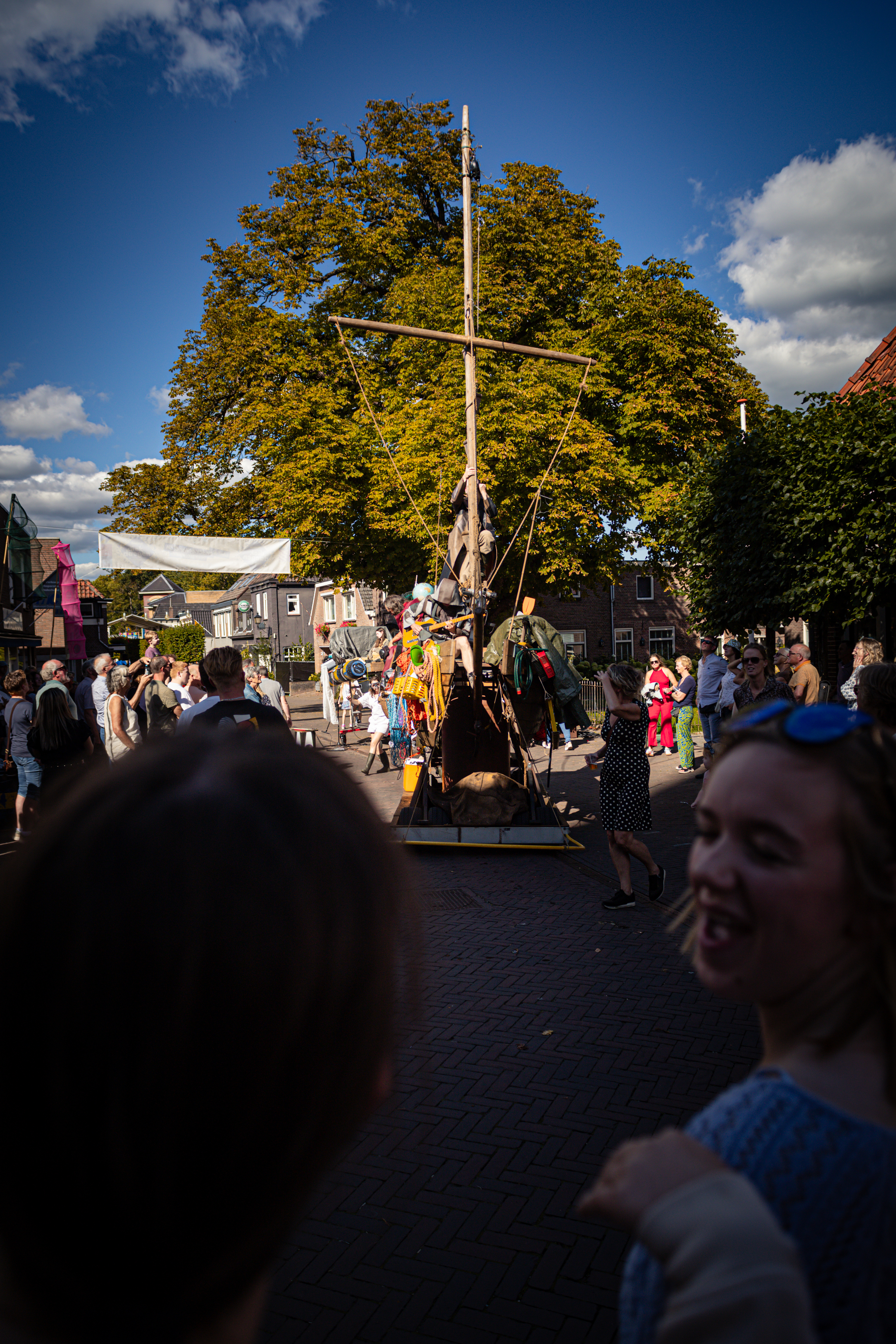 a group of people standing in front of a large ship, one with blue hair and green glasses.
