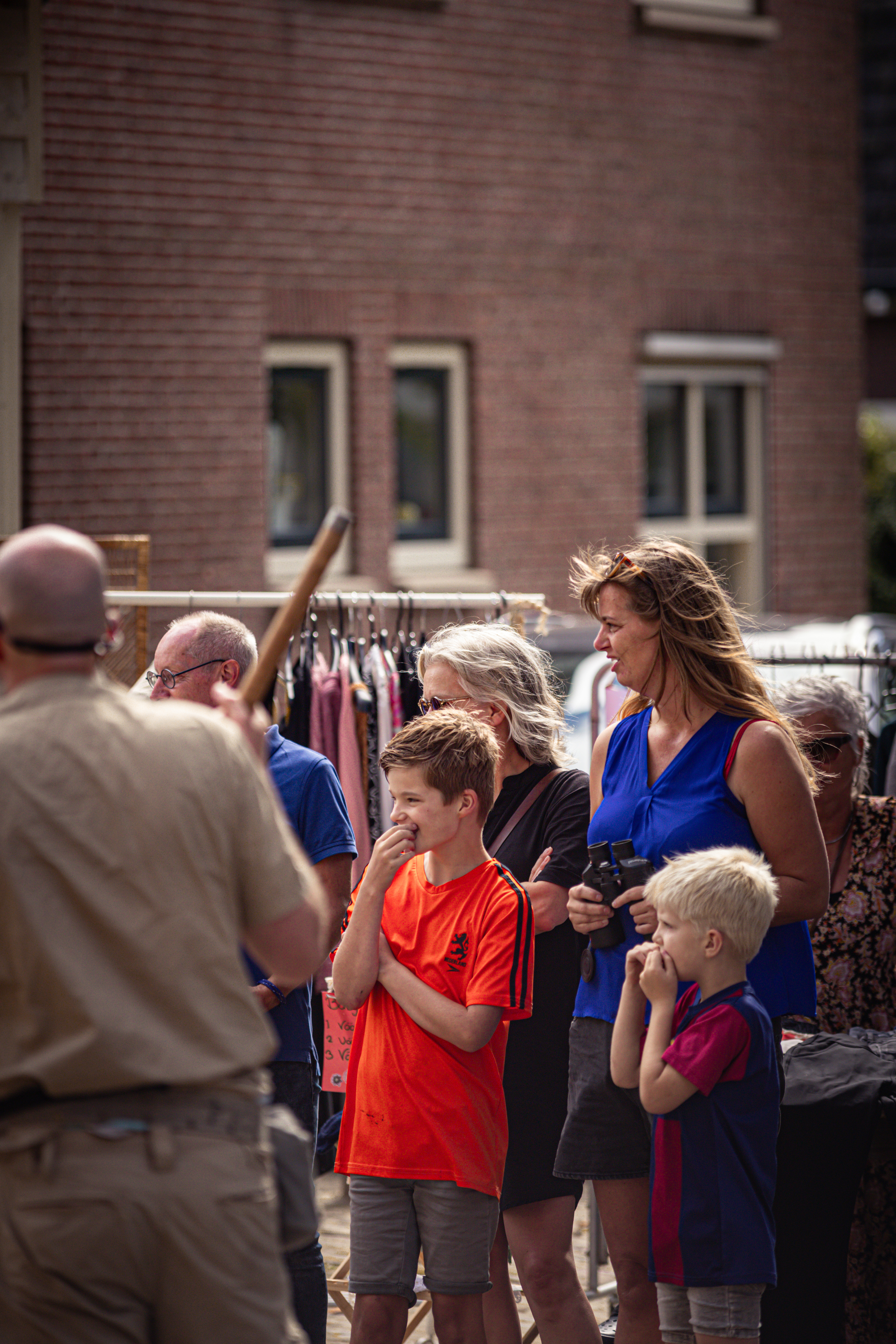 A woman in a blue shirt, with a child and another man looking at the camera.