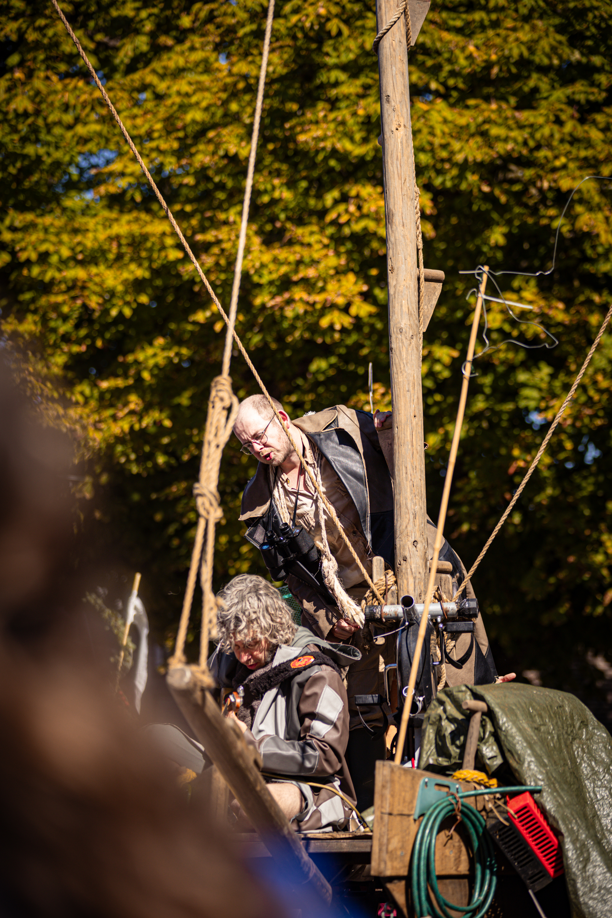 A man is performing in the V.IJ.F. Festival on a platform with ropes and sticks.