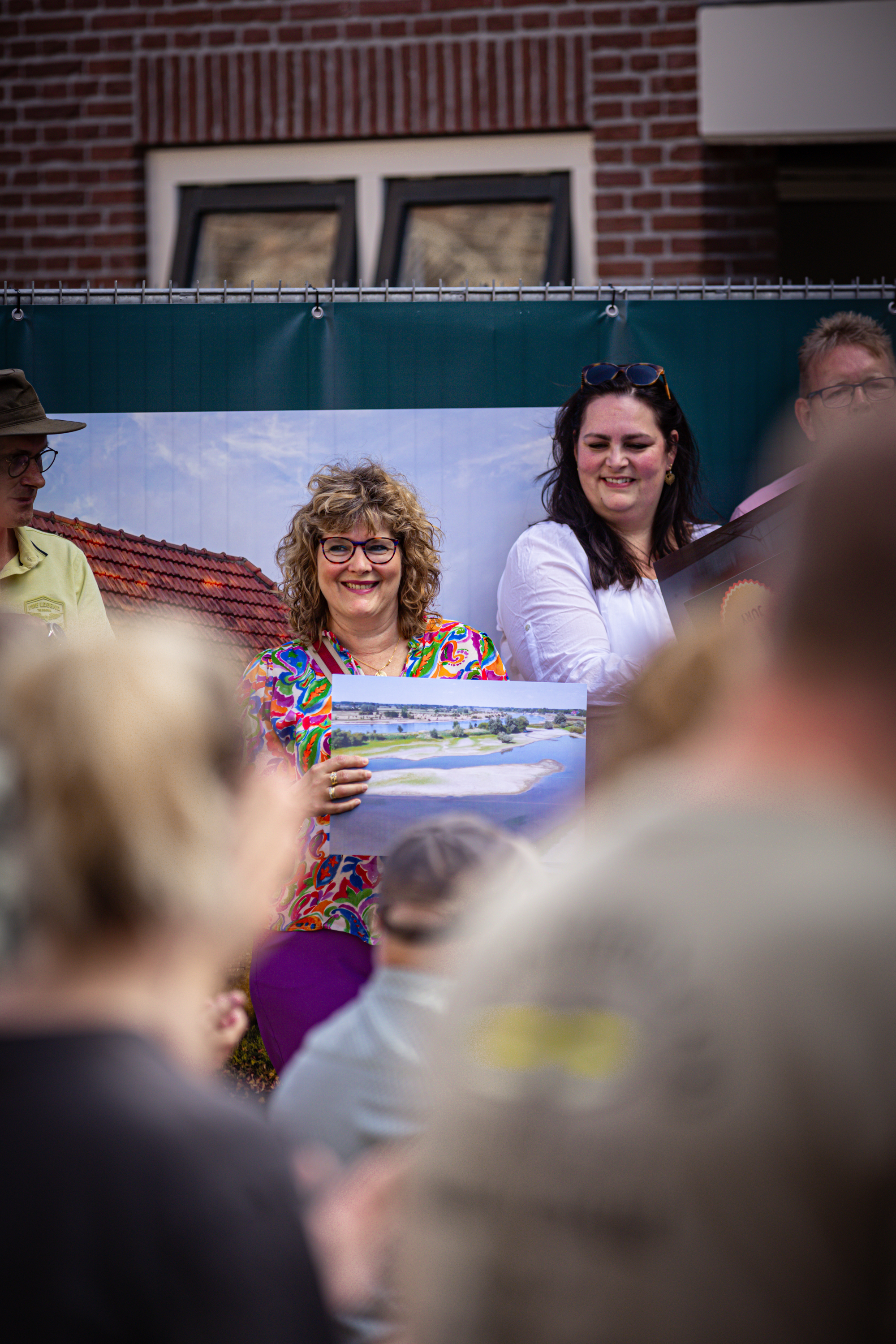 A woman is showing a picture of the beach at the V.I.J.F. Festival to a crowd.