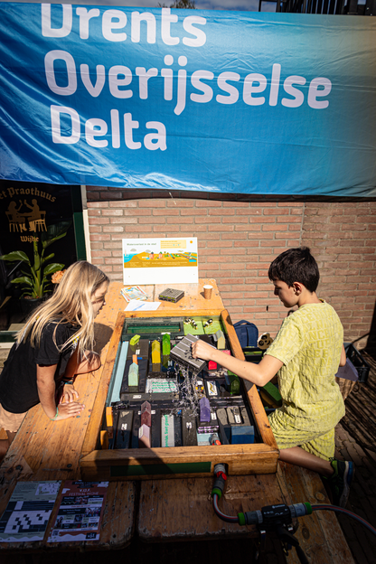 Two people are playing with a toy set under a banner that reads "Overijssel Delta".