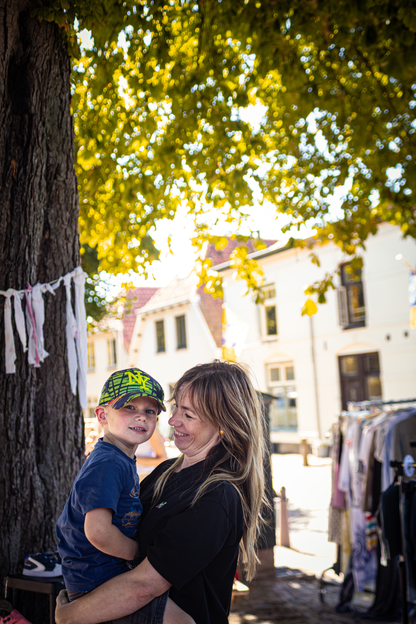 A young child and a woman standing near a tree under a sign that says "Festival".