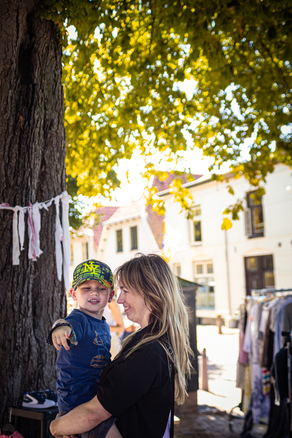 A woman holds a child on her arms with a green helmet on.
