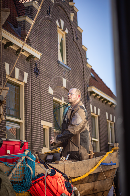 A man is sitting on a wooden bench with fishing rods in his hand.