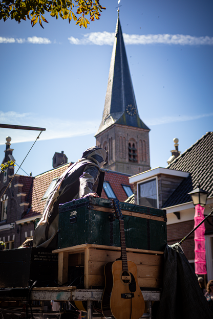 A man is playing a guitar outside near a church with a steeple.