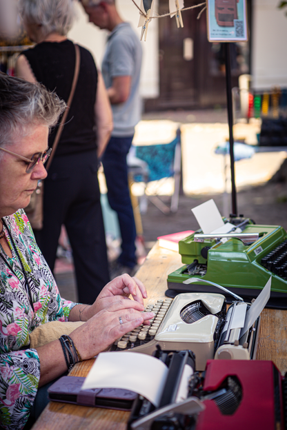 A woman is typing on a typewriter at the V. J. F. Festival.