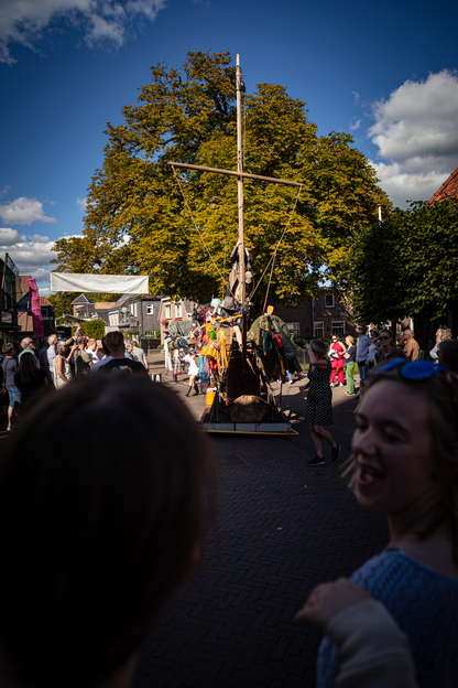 a group of people standing in front of a large ship, one with blue hair and green glasses.