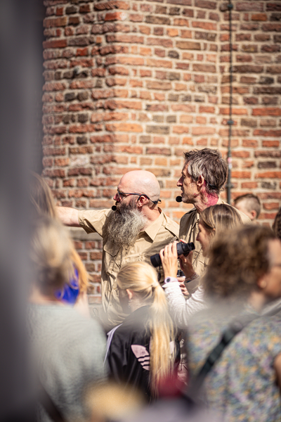 A man with a beard in front of a brick wall at the V.I.J. Festival.