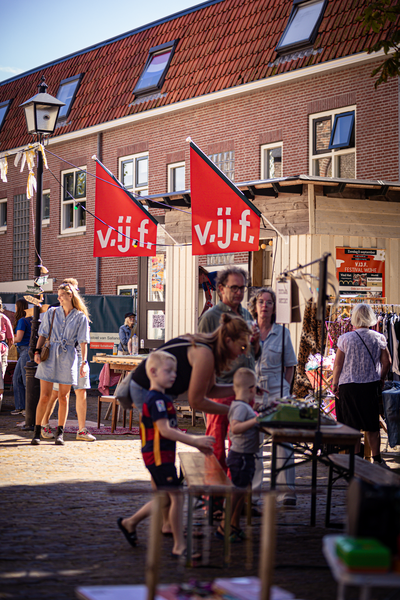 A family at a small fair with banners that say "V" on them.