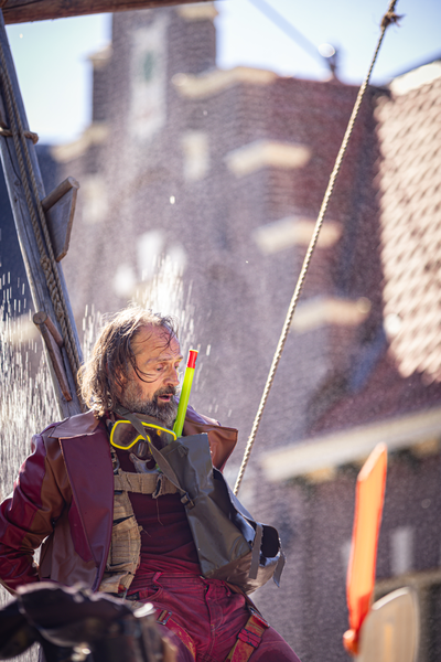 A man holding a yellow toothbrush and standing in front of the V.J.F. Festival sign.