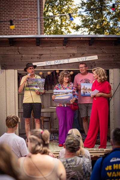 Four people on a wooden stage in front of a sign that reads "De Mee Van Vlaarderpark".