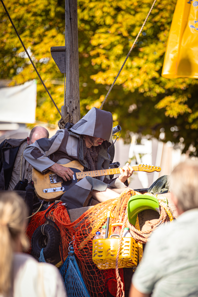 A man in a gray and black outfit playing guitar on stage.