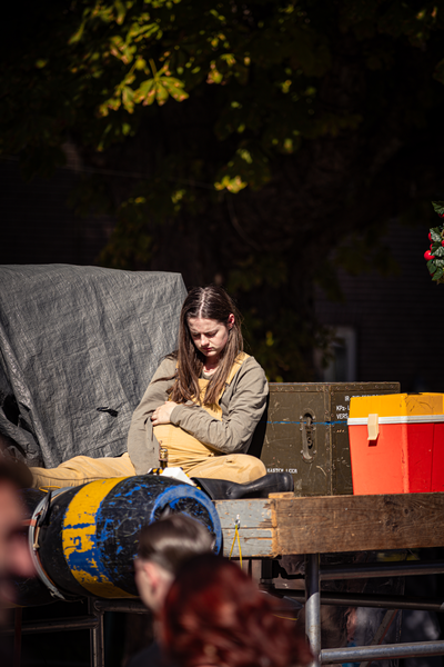 A young woman sitting on a train with luggage around her.
