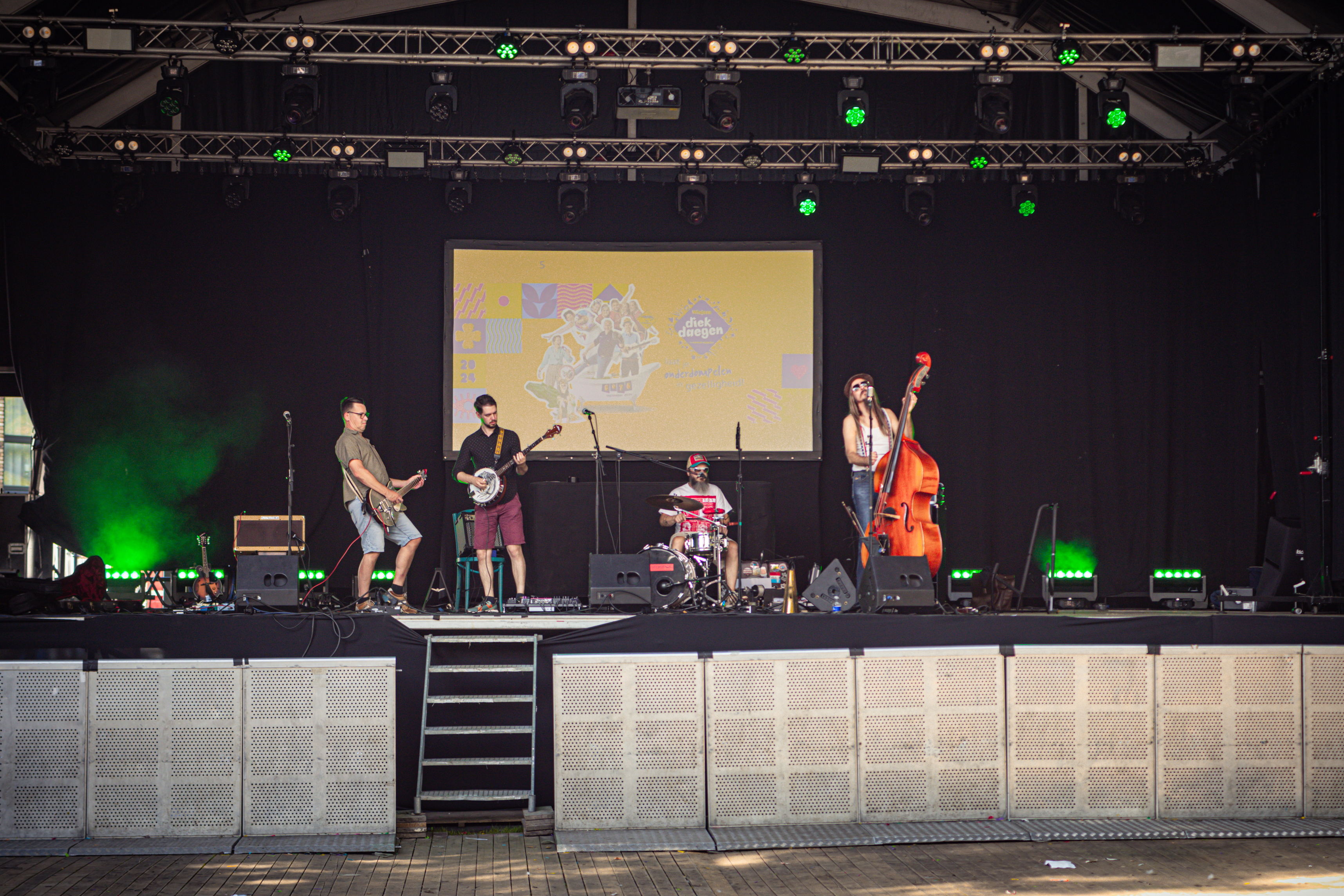 Four people performing music on a stage with musical instruments.