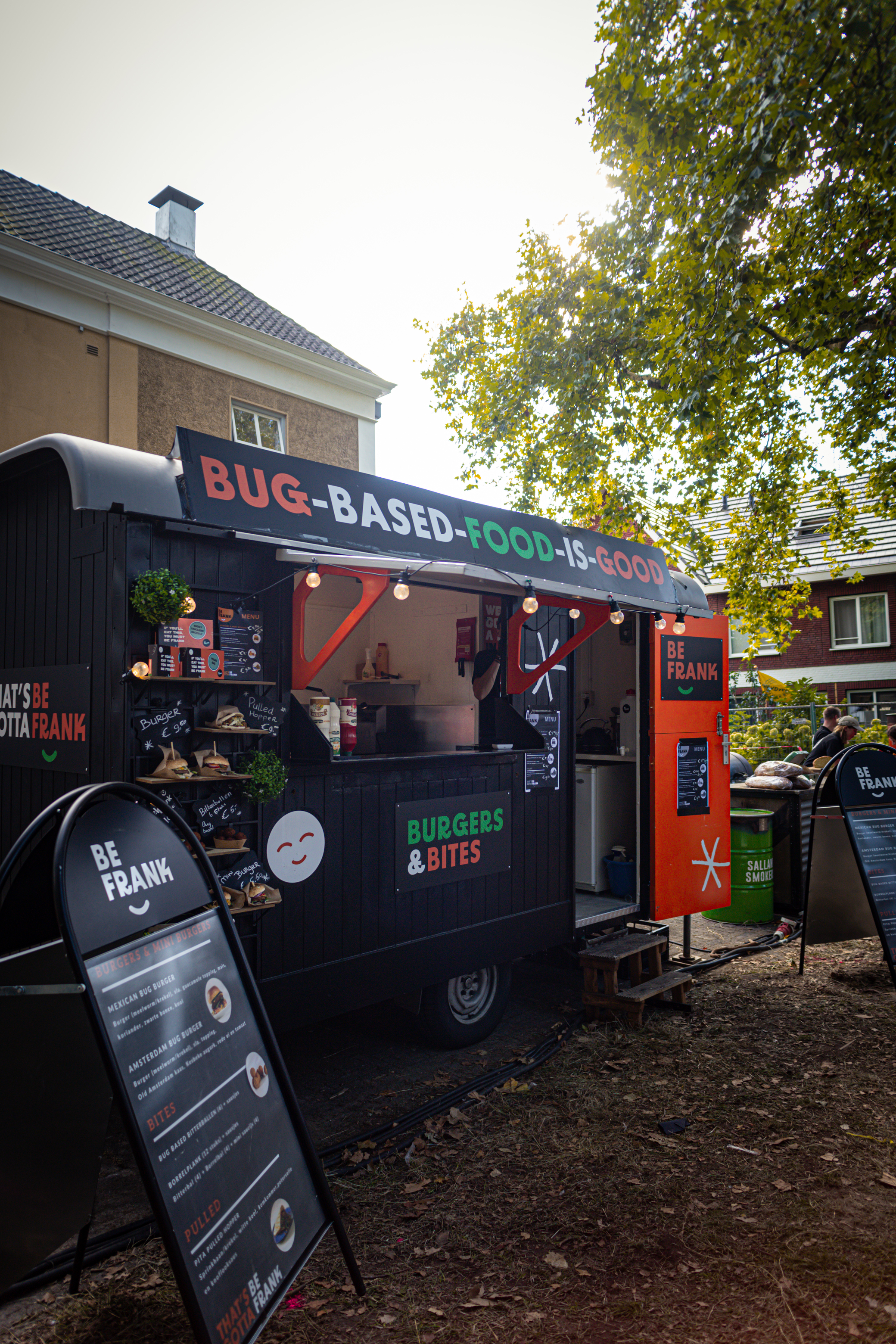 A black food truck that is selling food and drinks.