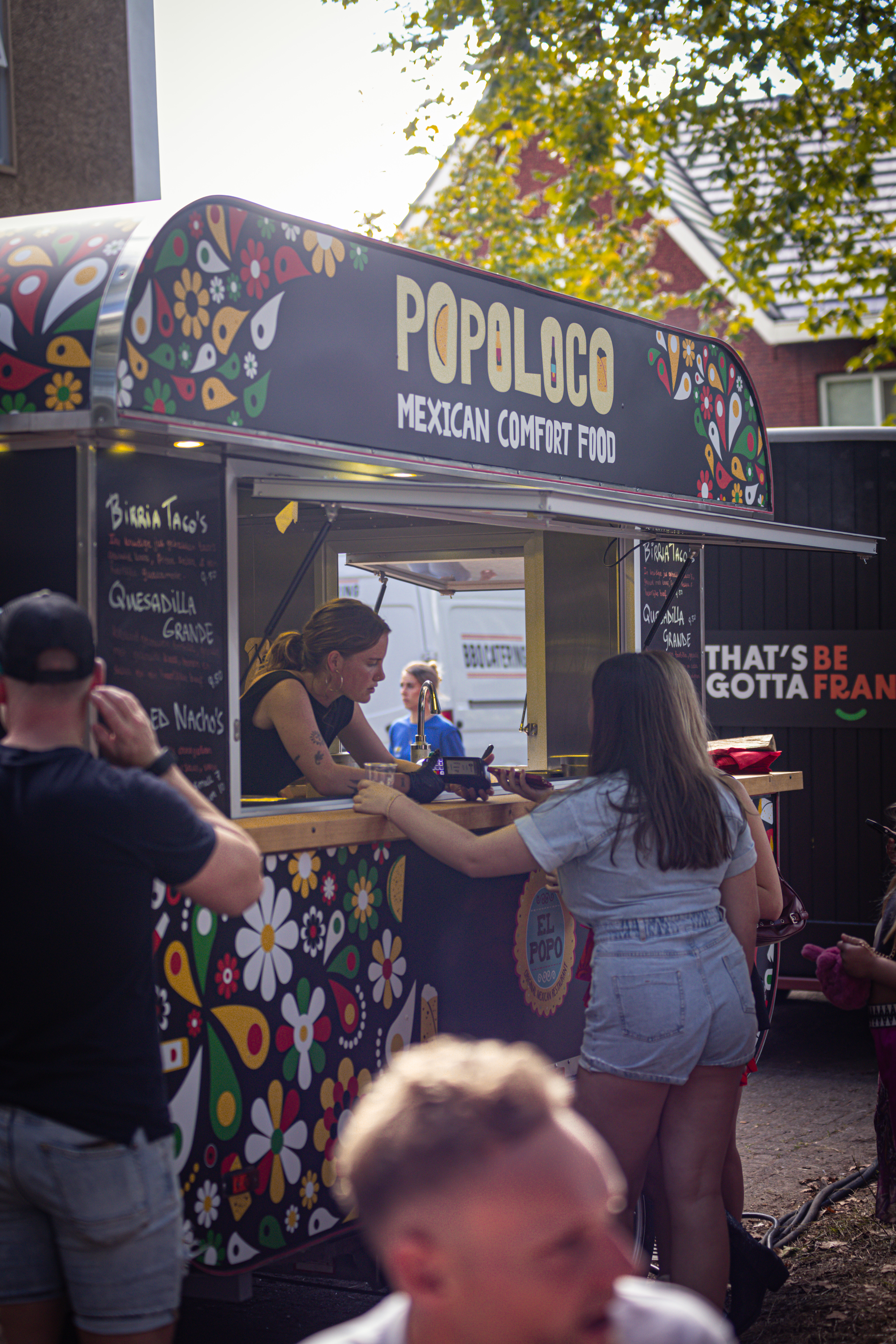 A food truck selling Mexican cuisine from a small white and black building.