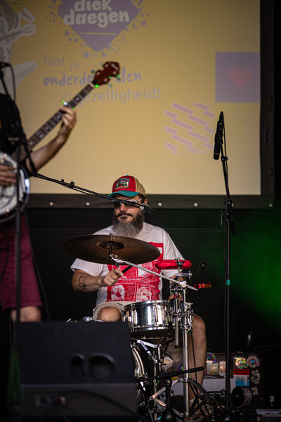 A man playing the drums and wearing a red and white shirt.