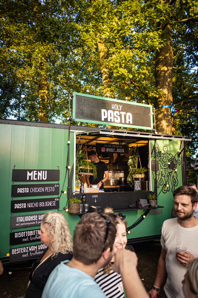 A green food truck named Pasta is open for business and ready to serve customers.