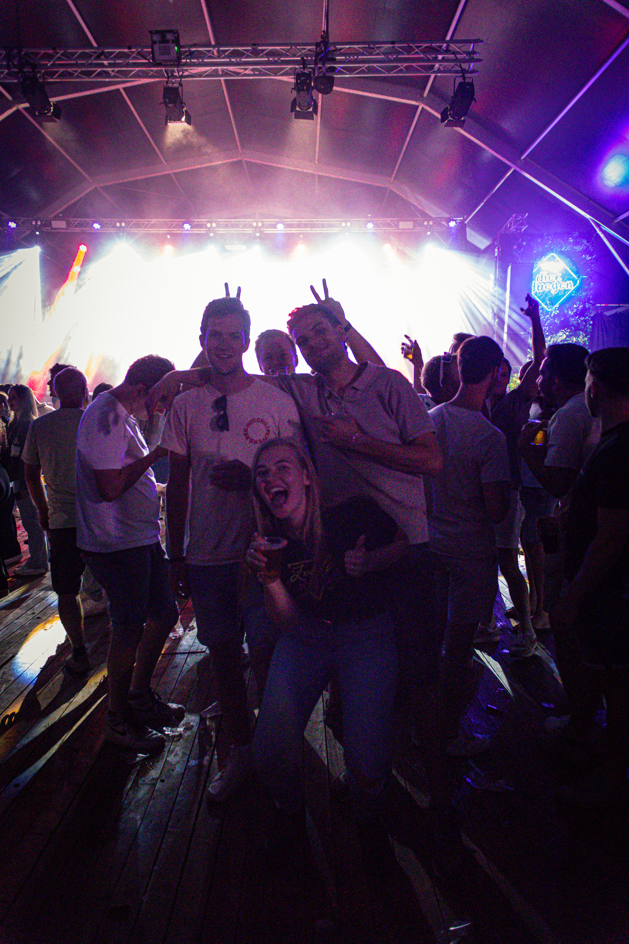 A group of friends standing together at a concert, having their pictures taken.