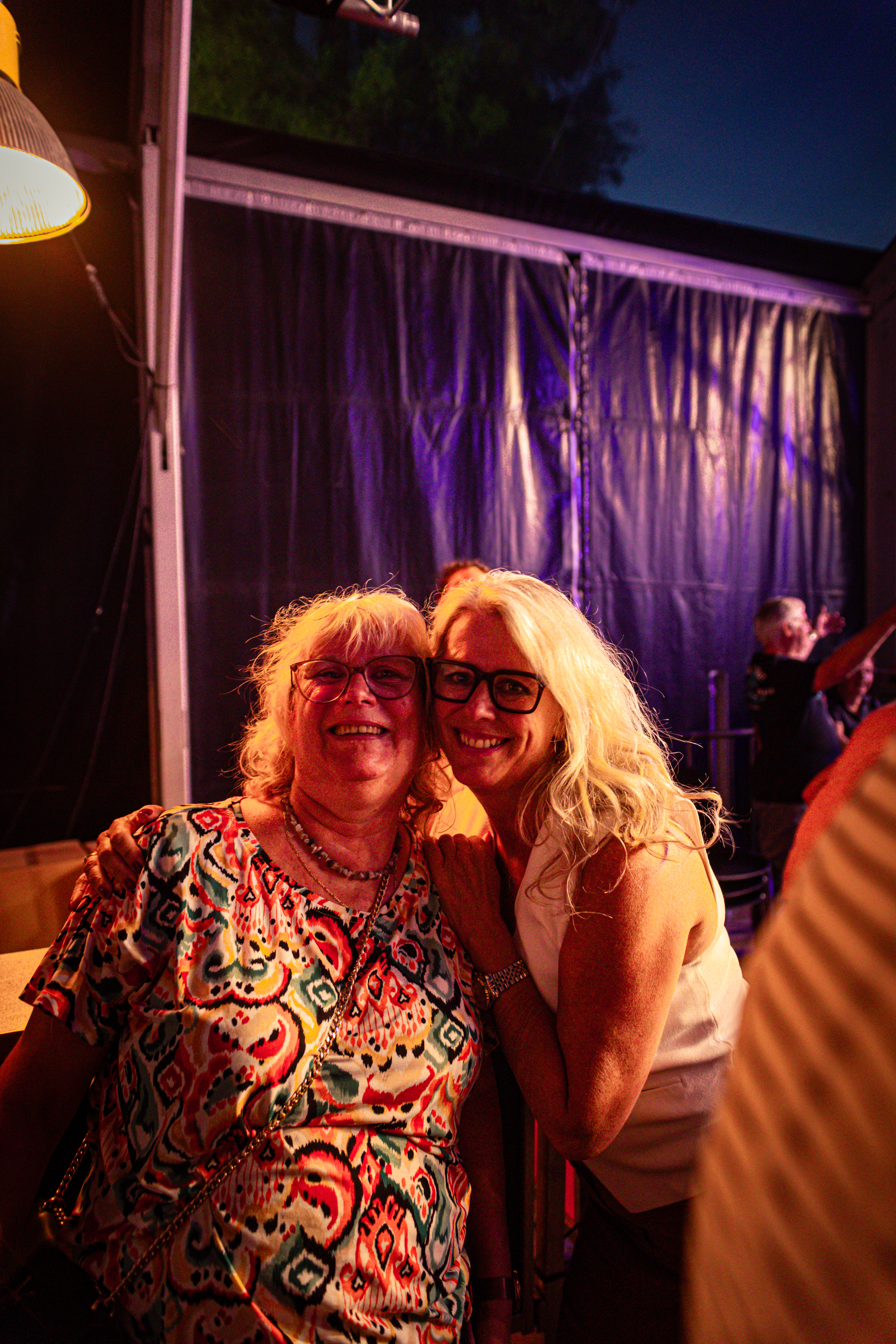 Twee oudere vrouwen genieten van elkaars gezelschap in een tent.