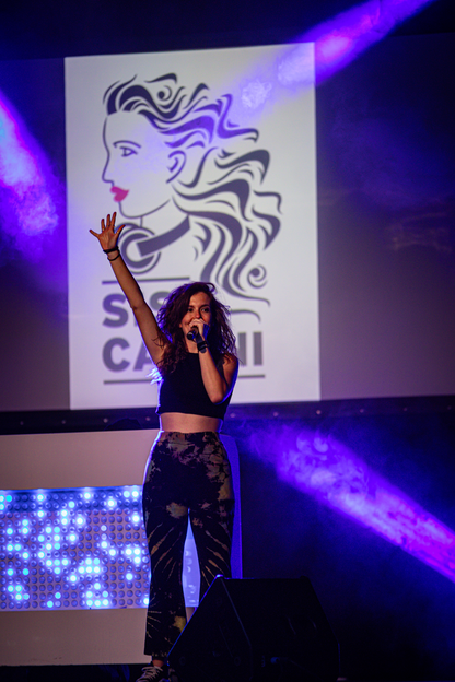 A woman on stage at a concert holding a microphone.